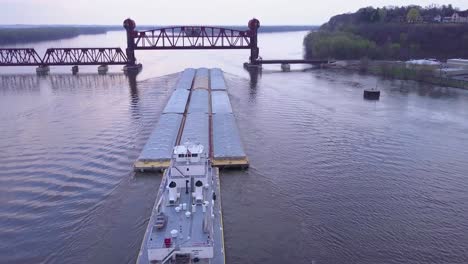 Eine-Schöne-Antenne-Eines-Lastkahns,-Der-Auf-Dem-Mississippi-Zu-Einer-Großen-Stahlzugbrücke-Fährt-1