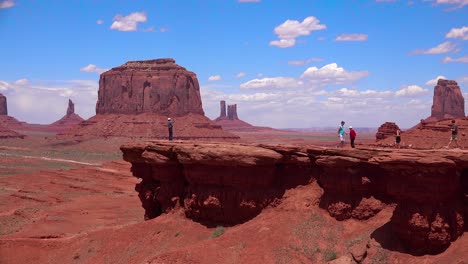 Tourists-walk-on-an-outcrop-in-front-of-Monument-Valley