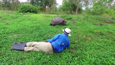 Traveling-shot-of-a-tourist-lying-on-the-ground-admiring-a-giant-land-tortoise-in-the-Galapagos-Islands-Ecuador-1