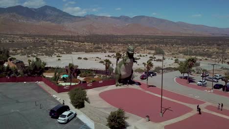 Vista-Aérea-over-a-giant-artifical-dinosaur-looming-over-visitors-as-a-roadside-attraction-in-the-Mojave-Desert-near-Cabazon-California