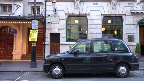 Un-Taxi-De-Londres-Está-Estacionado-Fuera-De-Un-Restaurante-O-Pub.