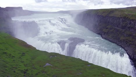 Der-Spektakuläre-Und-Massive-Wasserfall-Gullfoss-Fließt-In-Island-Mit-Touristen-Auf-Einer-Klippe-In-Entfernung-1