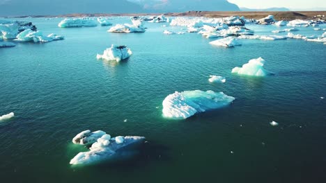 Drone-aerial-over-icebergs-moving-in-a-glacial-bay-Jokulsarlon-glacier-lagoon-Iceland-suggesting-global-warming