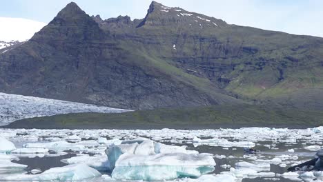 Ein-Klimaforscher-Fährt-In-Einem-Zodiac-Boot-über-Die-Riesige-Gletscherlagune,-Die-Mit-Eisbergen-Bei-Fjallsarlon-Island-Gefüllt-Ist,-Deutet-Auf-Globale-Erwärmung-Und-Klimawandel-Hin