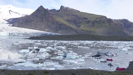 Klimaforscher-Fahren-In-Zodiac-Booten-über-Die-Riesige-Gletscherlagune,-Die-Mit-Eisbergen-Bei-Fjallsarlon-Island-Gefüllt-Ist,-Deutet-Auf-Globale-Erwärmung-Und-Klimawandel-Hin