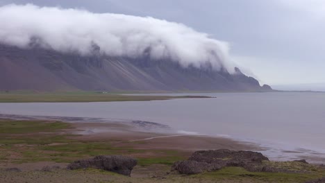 Aufnahme-Von-Bemerkenswert-Schönen-Fjorden-In-Island-Mit-Wolken-Und-Nebel,-Die-über-Die-Spitze-Rollen