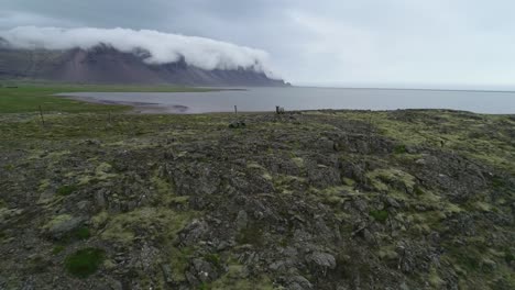 Atemberaubende-Luftaufnahme-Von-Bemerkenswert-Schönen-Fjorden-In-Island-Mit-Wolken-Und-Nebel,-Die-über-Die-Spitze-Rollen-Und-Ziegen-Im-Vordergrund-1