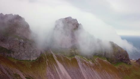 Luftaufnahme-Von-Bemerkenswert-Schönen-Fjorden-In-Island-Mit-Wolken-Und-Nebel,-Die-über-Die-Spitze-Rollen