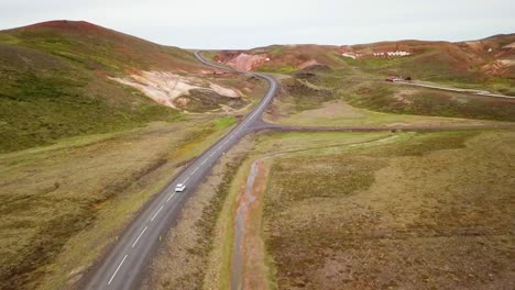 Aerial-of-a-white-car-traveling-on-a-lonely-road-in-Iceland