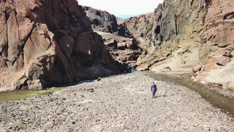 Aerial-over-a-woman-walking-into-a-deep-and-mysterious-canyon-in-Askja-central-highlands-of-Iceland