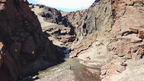 Aerial-over-a-woman-walking-into-a-deep-and-mysterious-canyon-in-Askja-central-highlands-of-Iceland-1