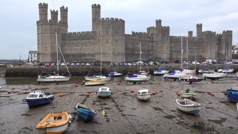 The-beautiful-Caernarfon-Castle-at-low-tide-with-beached-boats-in-Wales