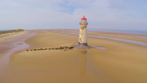 A-magnificent-vista-aérea-shot-of-the--Point-of-Ayr-lighthouse-in-Wales-with-weathered-fence-in-foreground