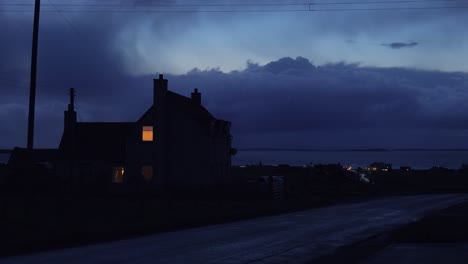 A-light-shines-in-the-upstairs-bedroom-of-a-lonely-house-in-the-countryside-at-night