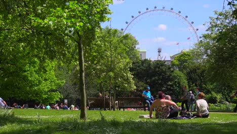 Pedestrians-walk-in-St-James-Park-in-London-with-London-Eye-background