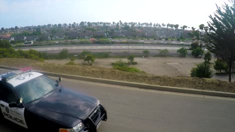 A-slow-motion-aerial-shot-over-a-police-car-traveling-on-a-road