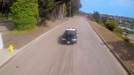 A-slow-motion-aerial-shot-over-a-police-car-traveling-on-a-road-1