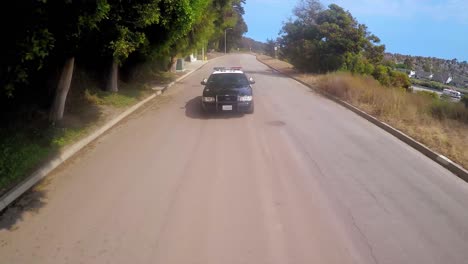 A-slow-motion-vista-aérea-shot-over-a-Policía-car-traveling-on-a-road-2