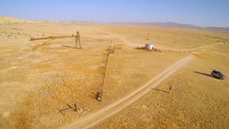 An-aerial-over-a-man-walking-to-his-car-near-an-abandoned-ranch-in-the-desert-of-the-Carrizo-Plain
