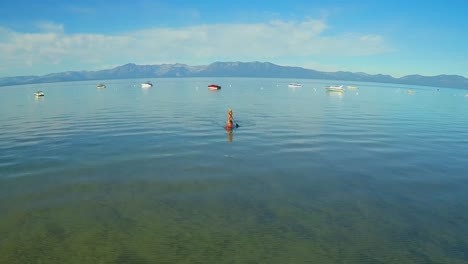 An-aerial-shot-of-a-woman-and-her-dog-paddle-boarding-on-Lake-Tahoe-3