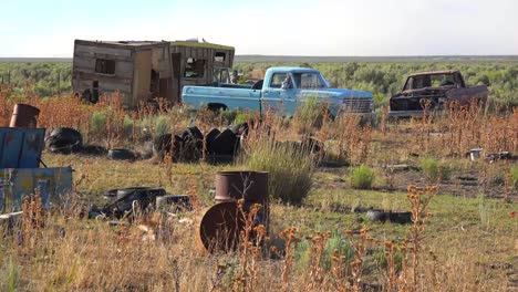 An-abandoned-mobile-home-in-the-desert-is-surrounded-by-old-trucks-and-cars-and-trash-5