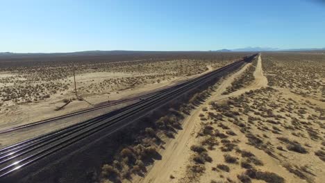 A-dramatic-aerial-over-a-freight-train-as-it-travels-at-a-high-speed-across-a-desert-landscape