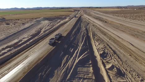 Dramatic-aerial-over-trucks-moving-along-a-highway-under-construction-1