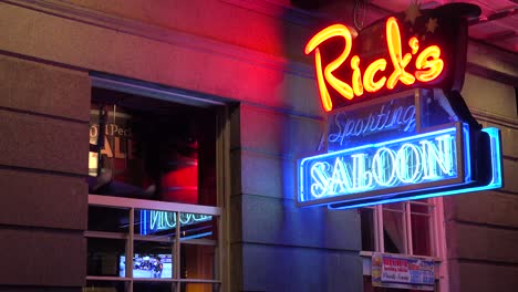 Neon-sign-for-Rick's-Saloon-on-Bourbon-Street-in-New-Orleans-at-night-and-legs-coming-out-of-window