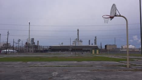 An-empty-basketball-court-stands-in-front-of-a-large-oil-refinery-1
