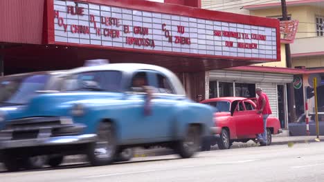 Men-load-up-an-old-car-outside-a-movie-theater-in-Havana-Cuba