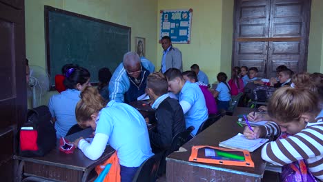Schüler-Lernen-In-Einem-Klassenzimmer-In-Kuba,-Während-Ein-Lehrer-Zuschaut