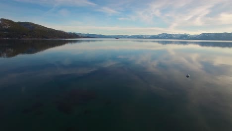 Una-Hermosa-Toma-Aérea-Sobre-El-Lago-Tahoe-En-Invierno-Con-Un-Barco-De-Vapor-De-Rueda-De-Paletas-En-La-Distancia
