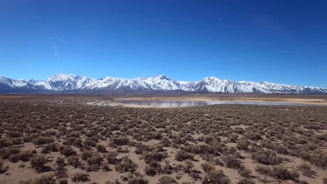 Una-Antena-Sobre-Una-Llanura-Geotérmica-En-Las-Montañas-De-Sierra-Nevada-Cerca-De-Mamut-California-Revela-Un-Lago-De-Montaña