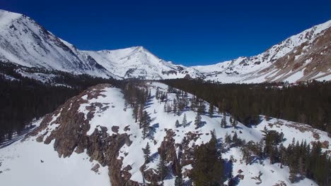 An-aerial-over-a-remote-abandoned-cabin-on-a-mountaintop-in-the-high-Sierra-Nevada-mountains-in-winter