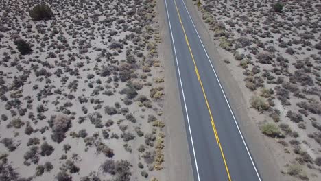 Aerial-above-a-4WD-traveling-on-a-dirt-road-in-the-Mojave-Desert-with-the-Sierra-Nevada-mountains-distant-3
