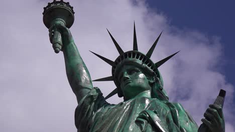 Eine-Patriotische-Aufnahme-Der-Freiheitsstatue-Vor-Einem-Bewölkten-Himmel-Mit-Der-Amerikanischen-Flagge-Im-Vordergrund-1