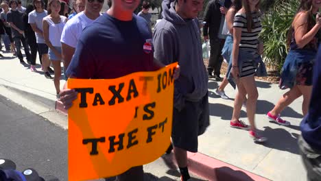 A-person-at-a-political-rally-holds-up-a-sign-saying-taxation-is-theft
