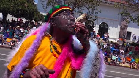 Un-Hombre-Fuma-Un-Gran-Porro-De-Marihuana-En-Las-Calles-De-Santa-Bárbara,-California,-Durante-El-Desfile-Del-Solsticio.