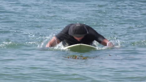 A-middle-aged-surfer-dude-paddles-his-board-in-the-waves-and-then-leaves-the-water