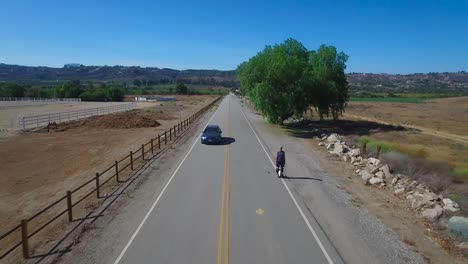 Aerial-footage-following-a-man-riding-an-electric-unicycle-down-a-road-in-California