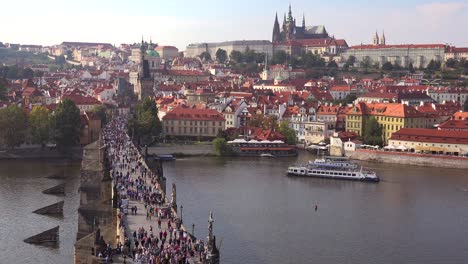 Hermoso-Día-Estableciendo-Tiro-Multitudes-Cruzando-El-Puente-De-Carlos-Sobre-El-Río-Moldava-En-Praga,-República-Checa