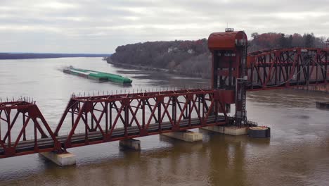 Drone-aerial-footage-of-a-huge-barge-traveling-under-a-railway-drawbridge-bridge-on-the-Mississippi-River-near-Burlington-Iowa