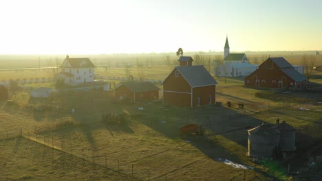 A-drone-vista-aérea-at-dawn-establishing-shot-over-a-classic-farmhouse-farm-and-barns-in-rural-midwest-America-York-Nebraska-1