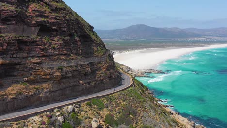 Eine-Luftaufnahme-Eines-Radfahrers,-Der-Auf-Einer-Gefährlichen-Schmalen-Bergstraße-Entlang-Der-Ocean-Chapmans-Peak-Road-In-Der-Nähe-Von-Kapstadt-Südafrika-Fährt-1