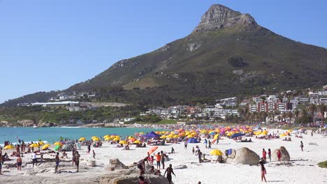 Establishing-shot-of-a-beautiful-busy-holiday-beach-scene-at-Camps-Bay-Cape-Town-South-Africa-with-Lions-Head-peak-background-1