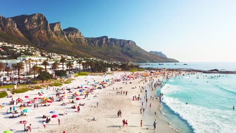 Spectacular-vista-aérea-over-a-crowded-and-busy-holiday-beach-at-Camps-Bay-Cape-Town-South-Africa-with-Twelve-Apostles-mountains-background-3