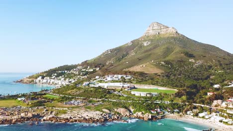 Aerial-moving-along-the-shoreline-of-Camps-Bay-Cape-Town-South-Africa-with-Lion's-Head-mountain-background