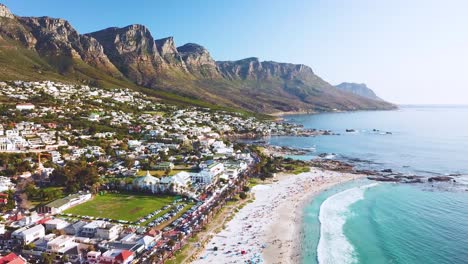 Aerial-moving-along-the-shoreline-of-Camps-Bay-Cape-Town-South-Africa-with-Twelve-Apostles-mountains-background-1
