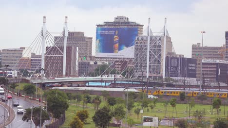 Establishing-shot-of-Johannesburg-South-Africa-with-Nelson-Mandela-bridge-and-passenger-train-foreground