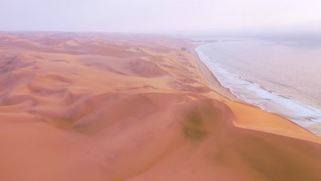 High-aerial-shot-through-clouds-and-fog-over-the-vast-sand-dunes-of-the-Namib-Desert-along-the-Skeleton-Coast-of-Namibia